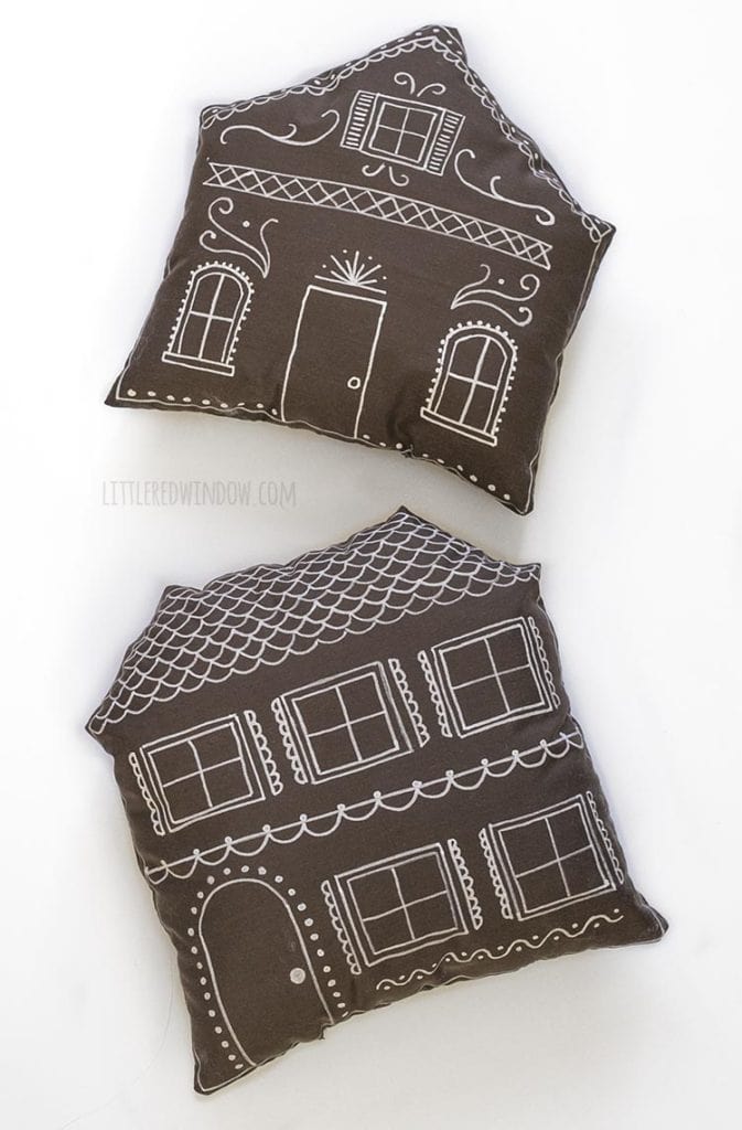 two brown pillows shaped and decorated like gingerbread houses on a white background