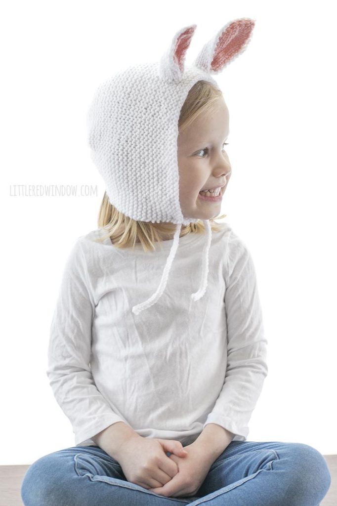 little girl wearing white knit bonnet with bunny ears and looking off to the right