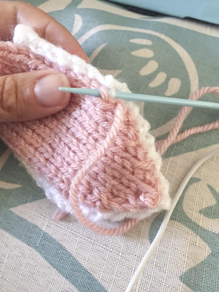 hand stitching two layers of knit bunny ears together with white yarn