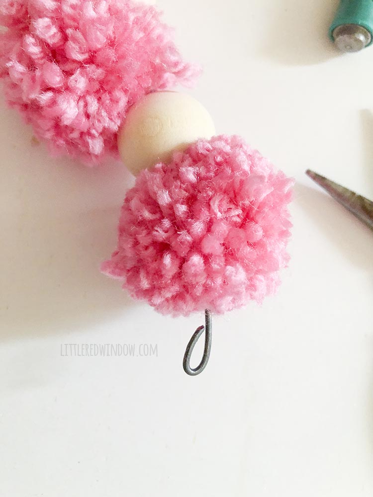 closeup of the end of the wire bent into a u shape after the last pom pom