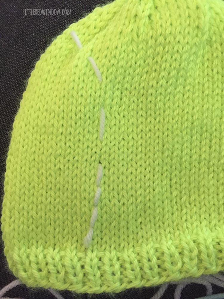 progress short of backstitch embroidery along a basting line on a bright green tennis ball hat