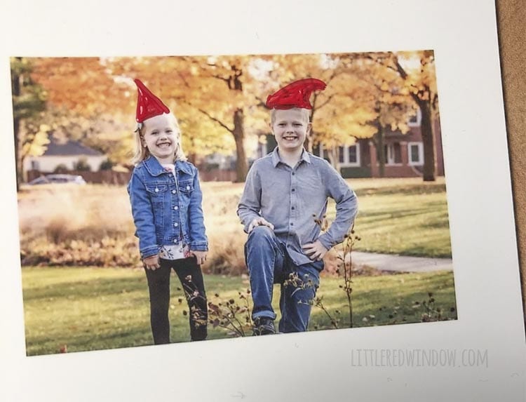 closeup of photo of two kids with the red part of santa hats painted on their heads