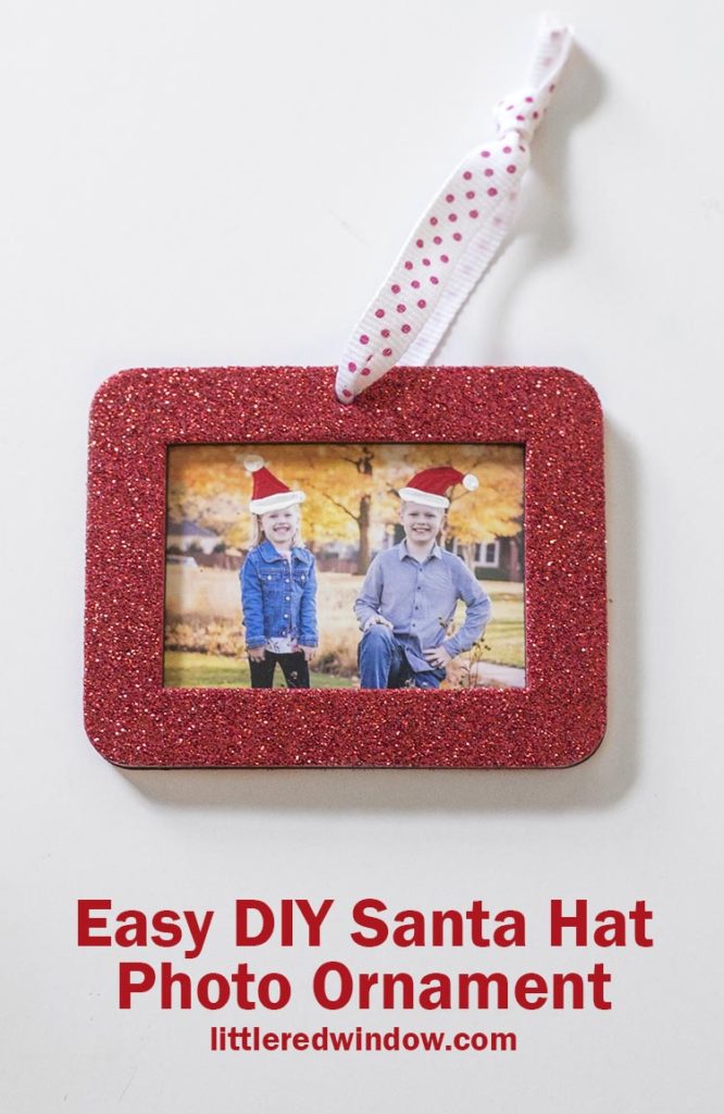 red rectangular glitter photo ornament with a photo of two kids with painted on santa hats inside on a white background