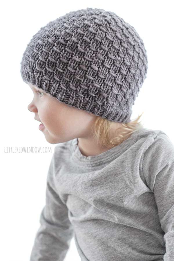 smiling girl looking off to the left and wearing a gray knit hat with horizontal elm gain stitch pattern