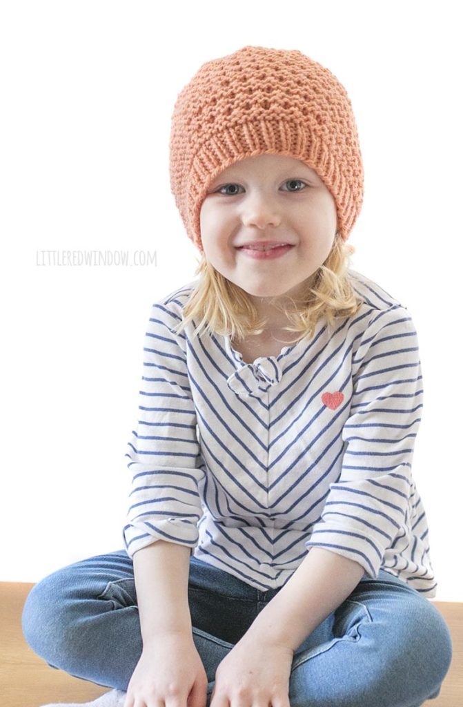 smiling girl in coral knit lace grid hat looking at the camera