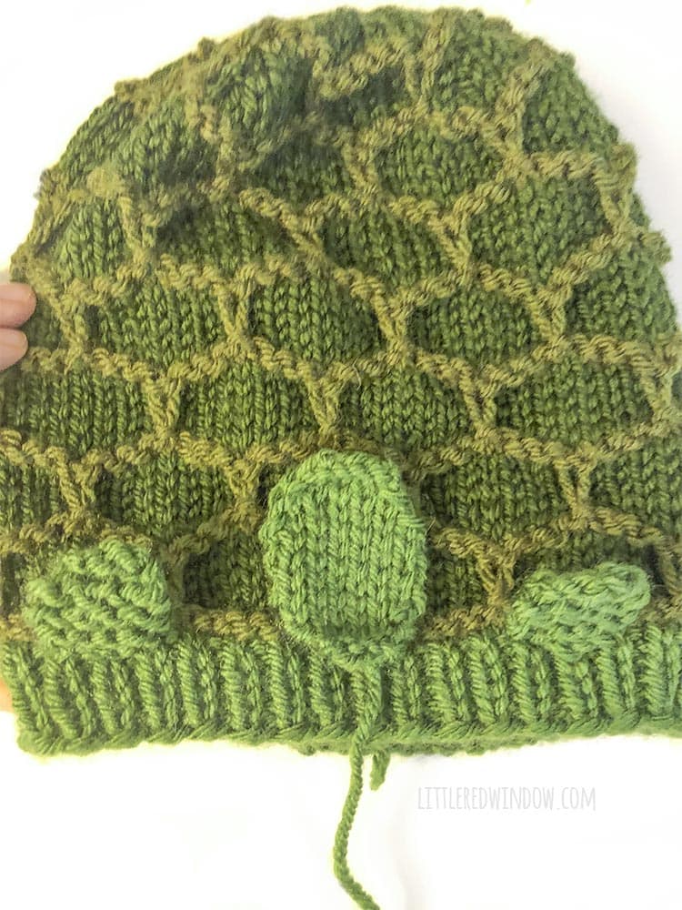 green turtle hat laid out with feet sewed on and face placed in place on top