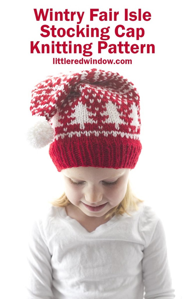 little girl looking down wearing a white shirt and red and white fair isle stocking cap with white Christmas trees on it