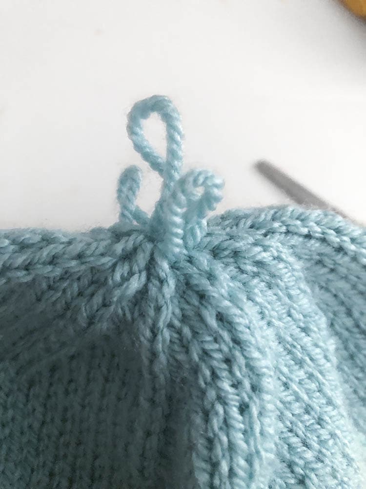 closeup of three small loops of yarn that look like feathers on the top of the bluebird hat