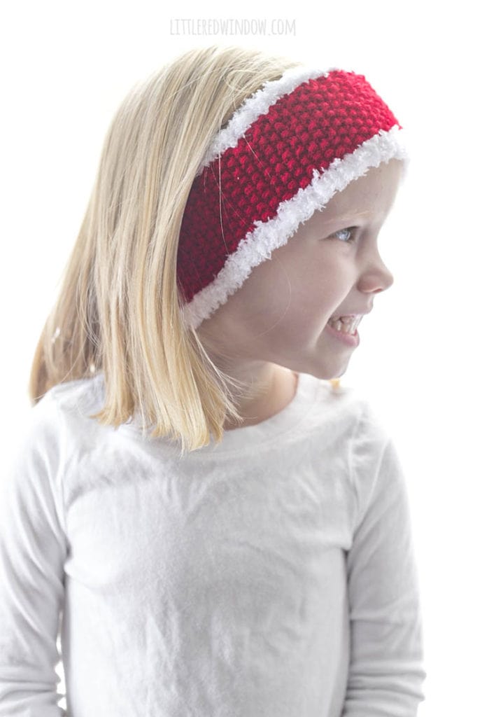 little girl wearing white shirt and wearing red headband with white trim looking off to the right