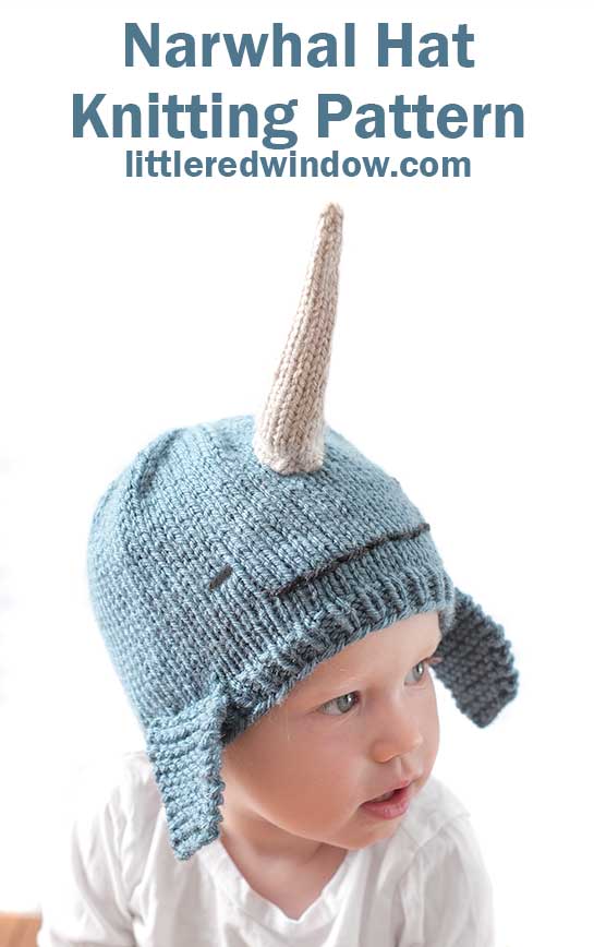 child in white shirt wearing a medium blue knit hat that looks like a narwhal in front of a white background looking off to the right