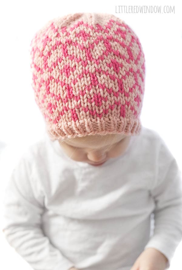 little girl wearing diamond geo hat in light and dark pink looking down at her lap