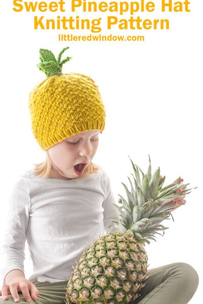 surprised kid holding a pineapple and wearing a knit hat that looks like a pineapple