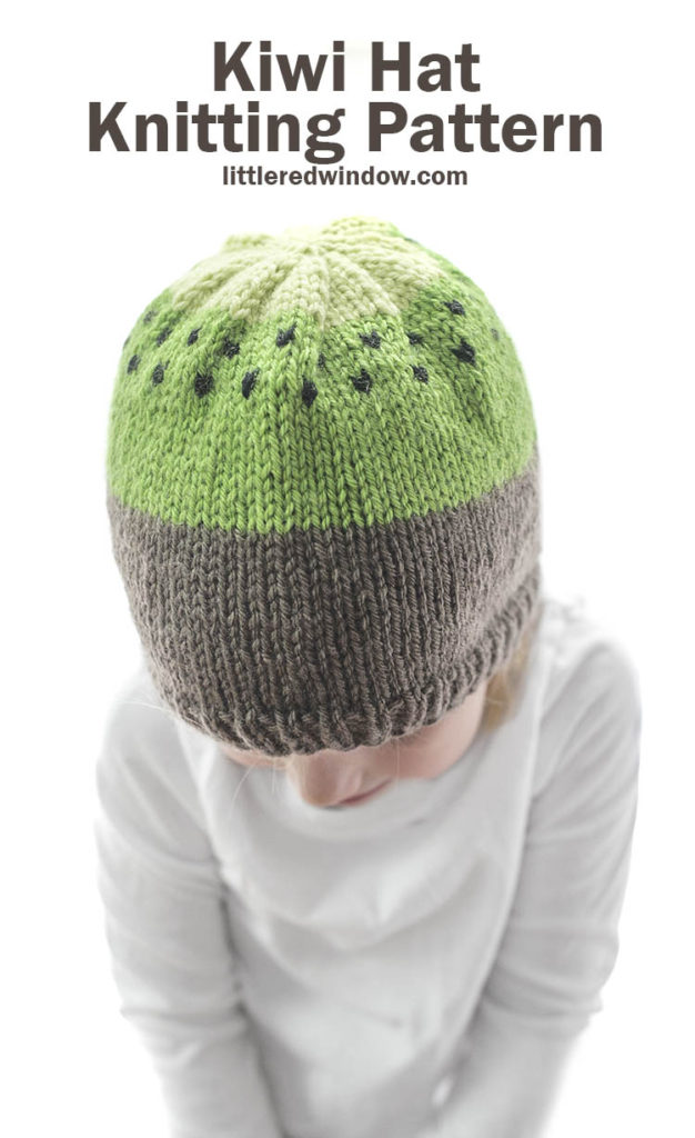 small child modeling brown and green knit kiwi hat knitting pattern with black seeds