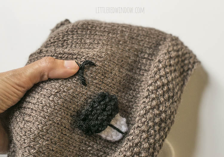 closeup of an upside down U shaped stitch with dark brown yarn that makes the eye of the beaver hat