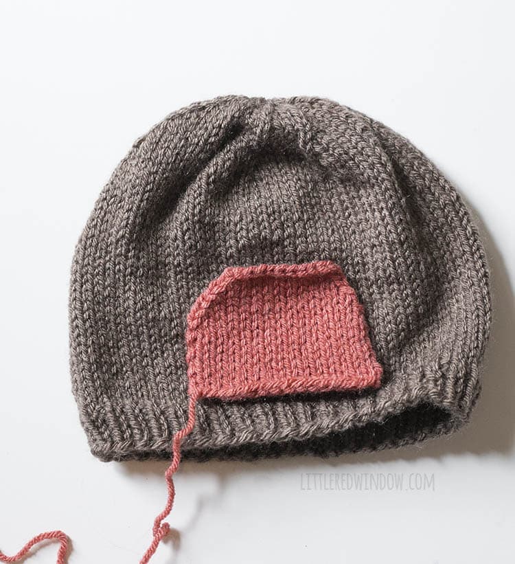brown knit hat with red half circle laid on top to show where to stitch the red breast to the robin hat