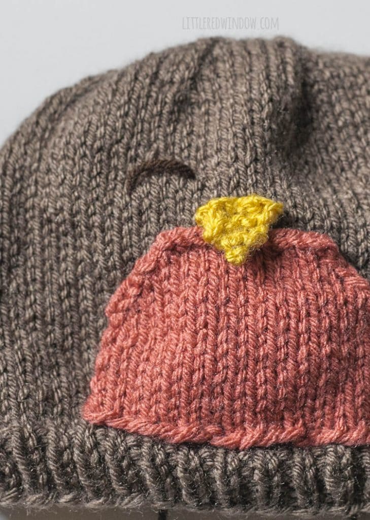 closeup of an upside down U shaped stitch with dark brown yarn that makes the eye of the robin hat