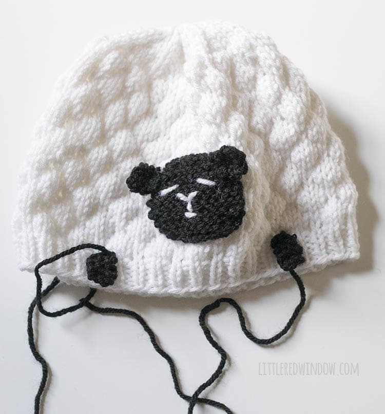 white sheep hat with face sewn on and two feel placed just above the brim on the front to show placement