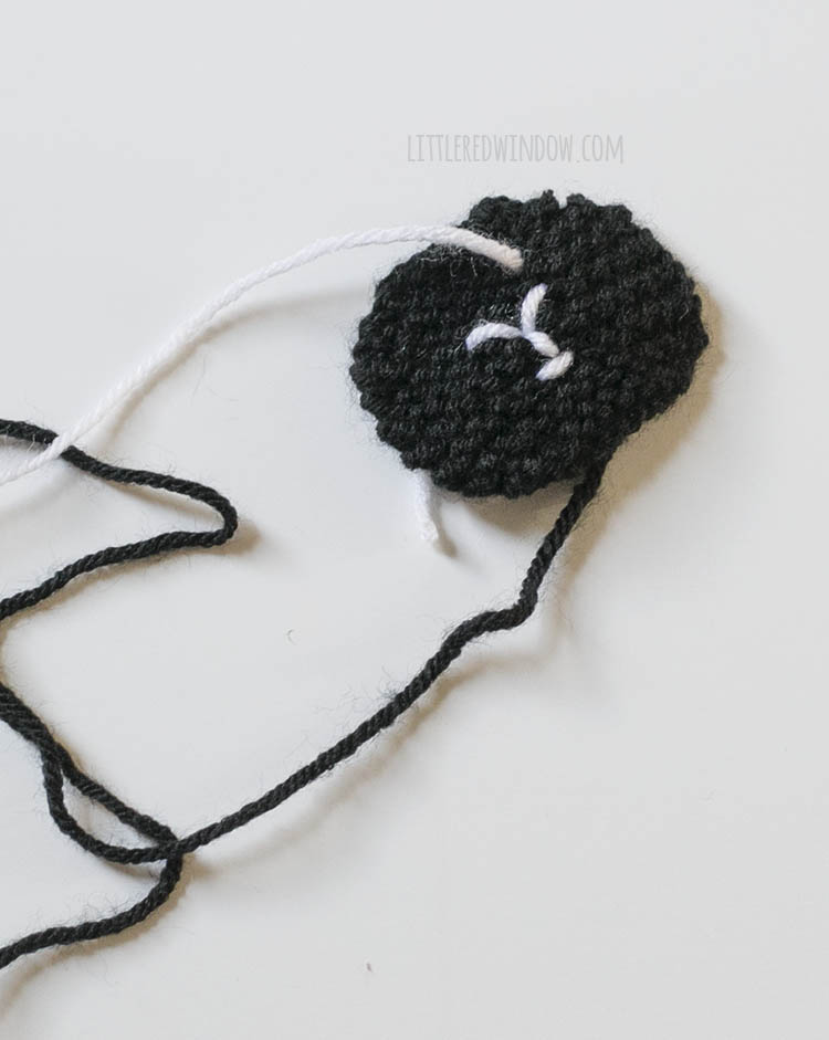 black circular sheep face with nose and mouth embroidered with white yarn