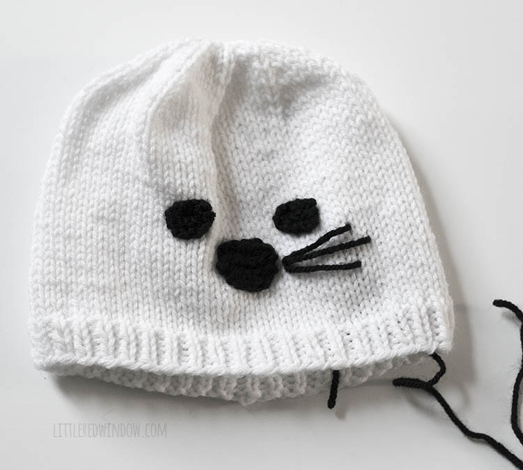white knit seal hat with three whiskers stitched on with black yarn