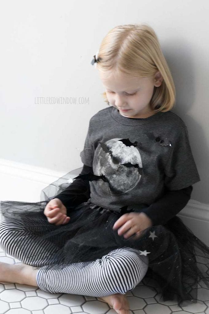 little girl sitting on the floor in a DIY bat girl costume covered in bats