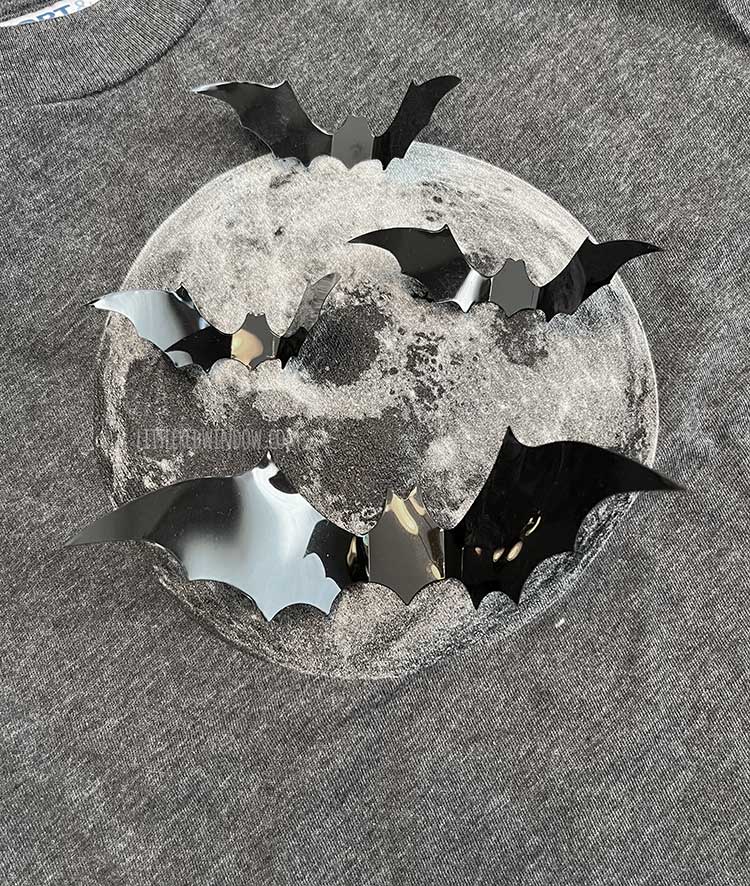 Plastic bat shapes laid out on a gray shirt with a full moon on it