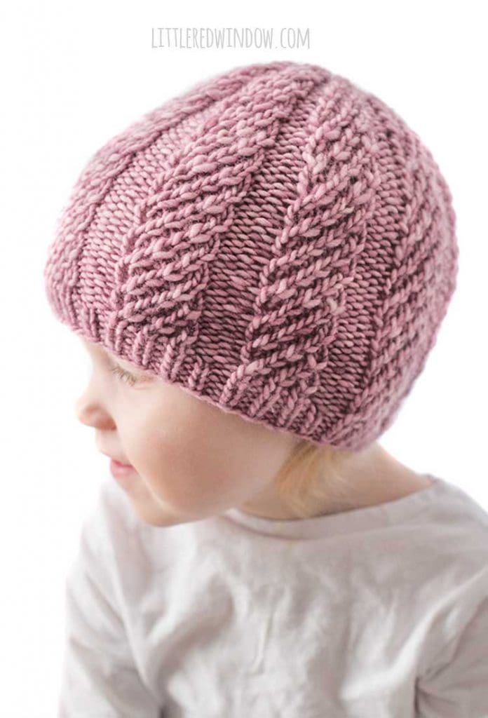 side view of baby wearing mauve knit hat and looking off to the left