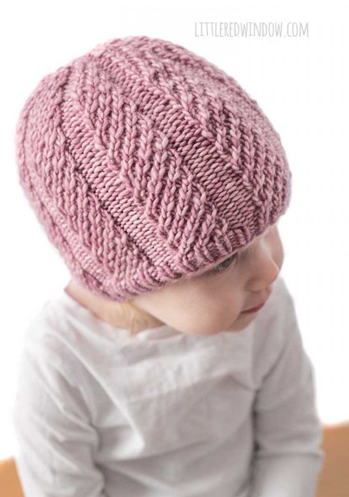 baby wearing mauve colored twisted rib hat and looking off to the right