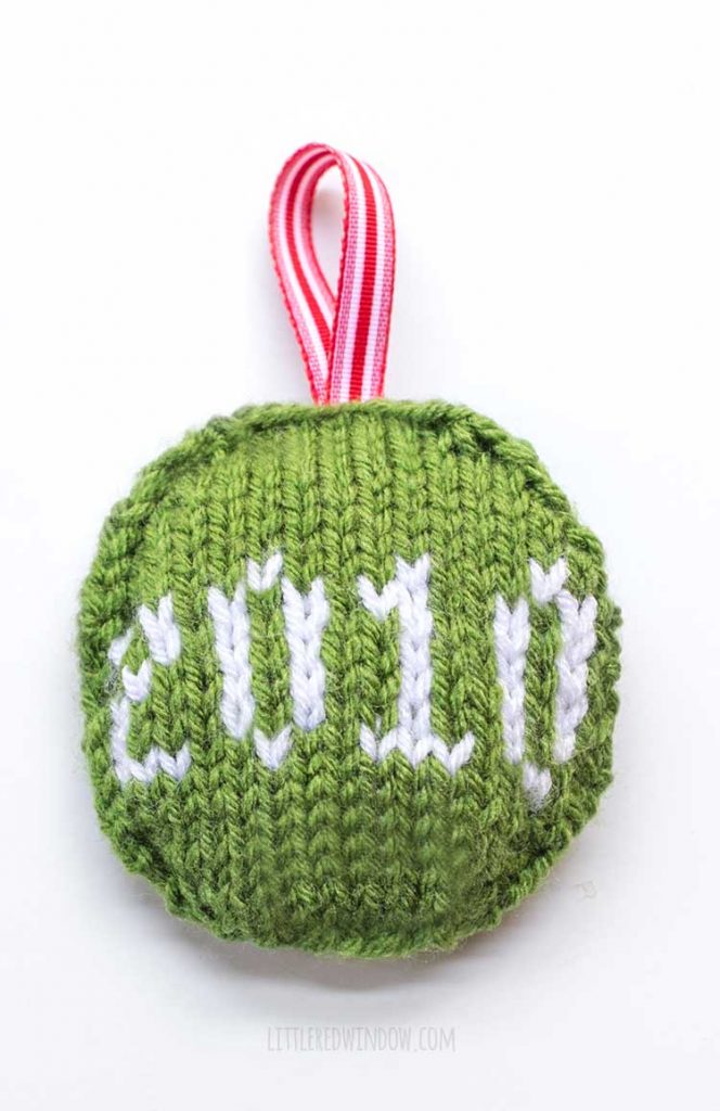 round green ornament with red ribbon loop with the date 2010 on the front in white