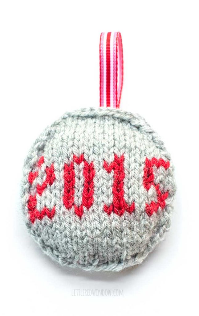 round gray ornament with red ribbon loop with the date 2015 on the front in red yarn