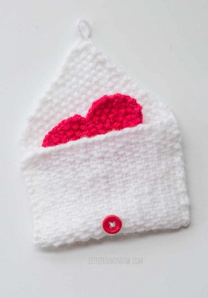 White knit envelope open with red heart peeking out
