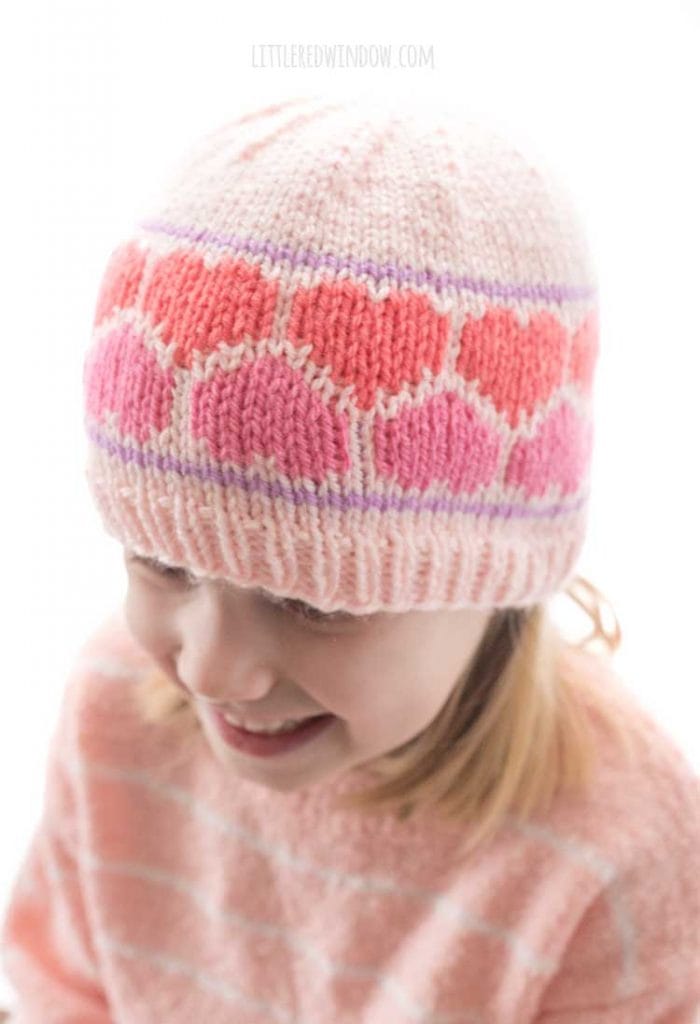 view from above of girl wearing pink knit hat with pink and coral heart pattern around the middle