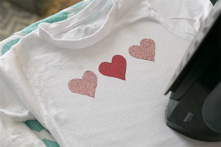 top view of three glitter hearts on the front of a child sized white tshirt