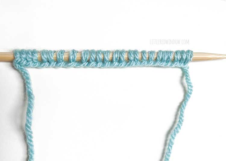 a knitting needle with light blue yarn showing the right side of the backwards loop cast on method