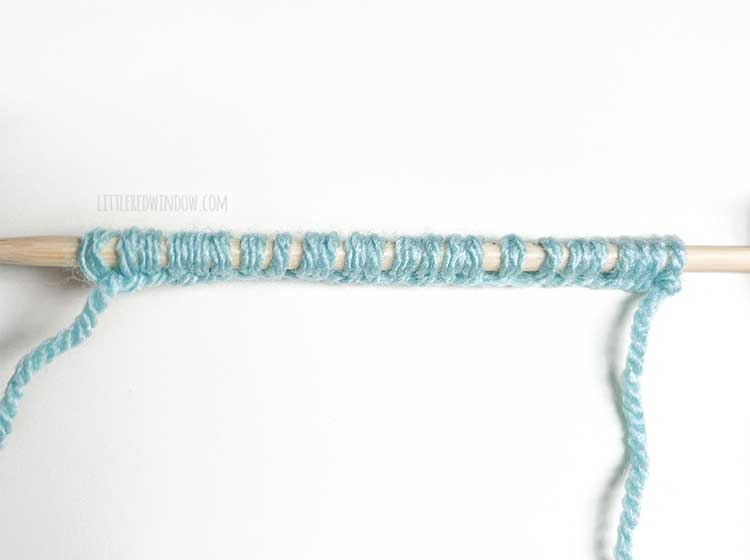 a knitting needle with light blue yarn showing the wrong side of the backwards loop cast on method