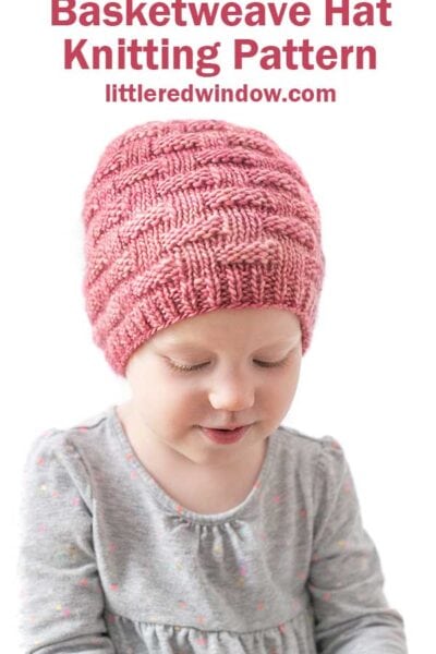 little girl wearing red knit hat with knit and purl basketweave texture looking down to the right