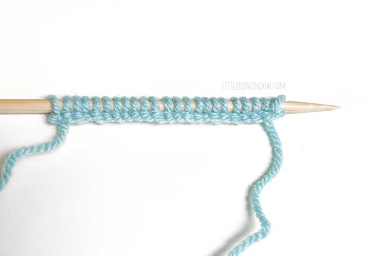 a knitting needle with light blue yarn showing the right side of the cable cast on method