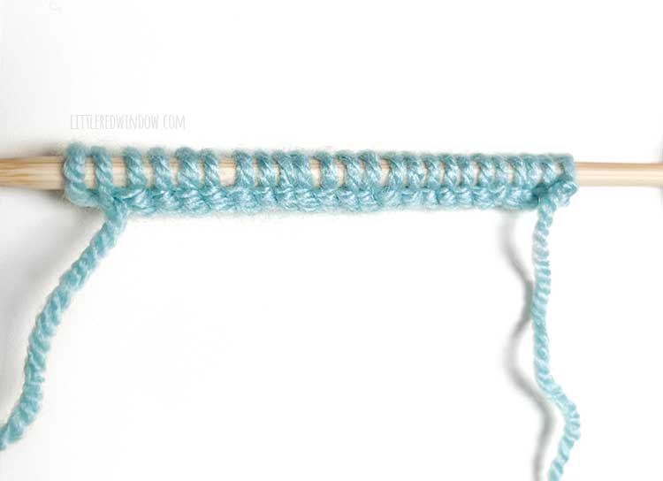 a knitting needle with light blue yarn showing the wrong side of the cable cast on method