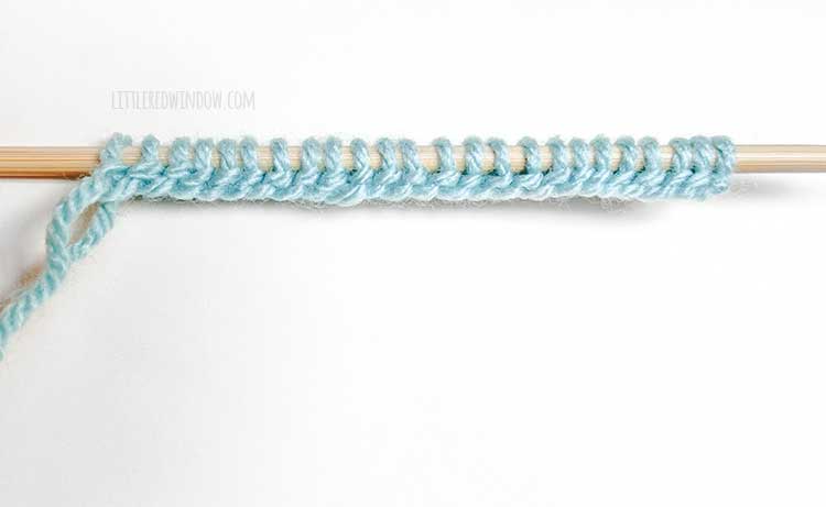 a knitting needle with light blue yarn showing the wrong side of the German twisted cast on method