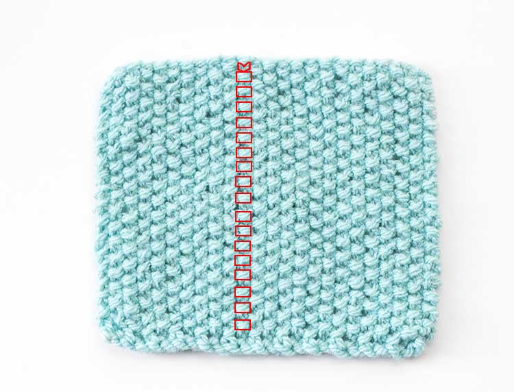 a square of light blue seed stitch knitting with the stitches in one column outlined in red
