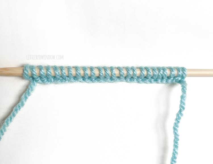 a knitting needle with light blue yarn showing the wrong side of the knitted cast on method