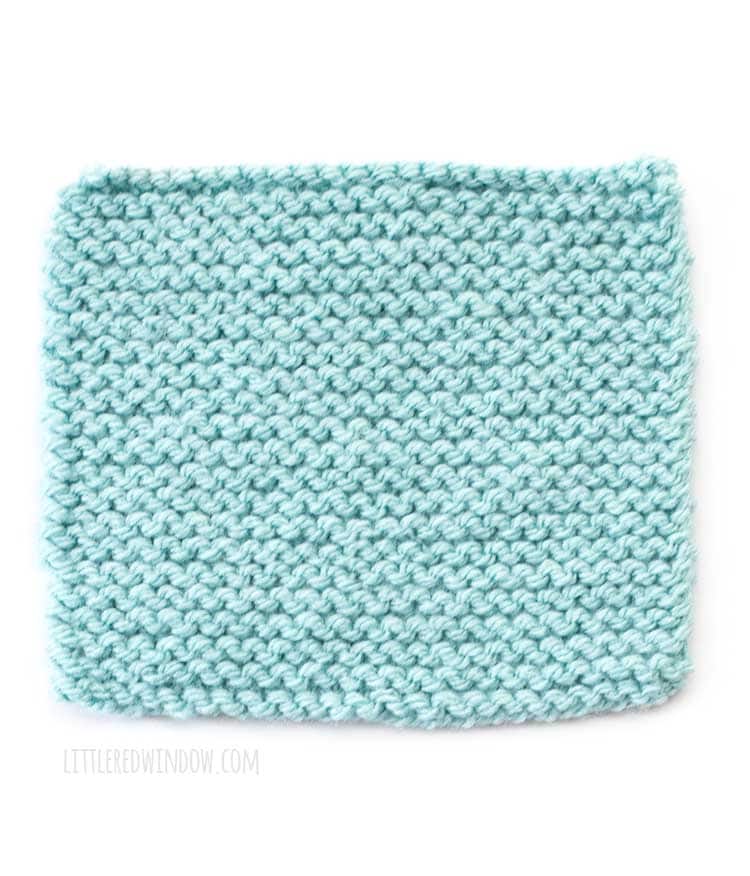 light blue square of garter stitch knitting showing the front right side of the fabric in front of a white background
