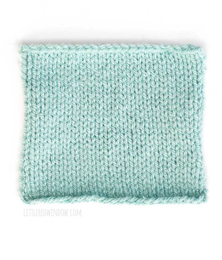 light blue square of stockinette stitch knitting showing the front right side of the fabric in front of a white background