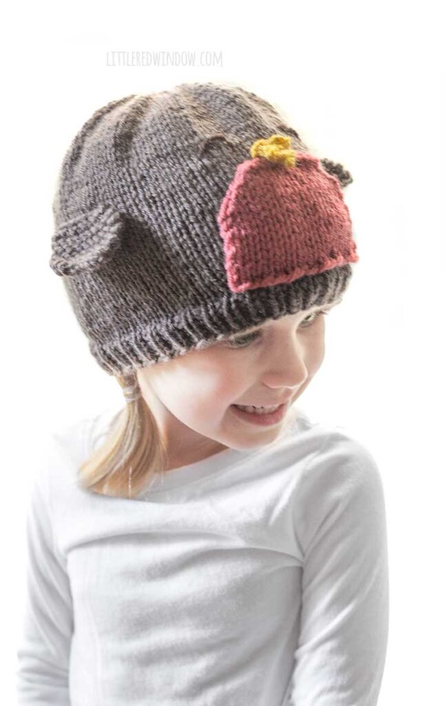 little girl wearing robin hat with wings looking down and to the right