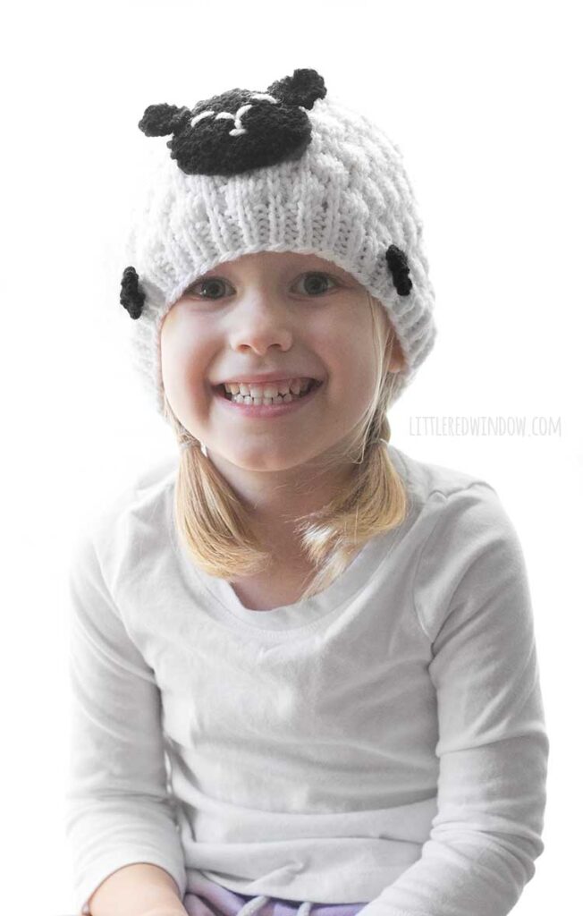 smiling girl wearing white and black knit hat that looks like a sheep