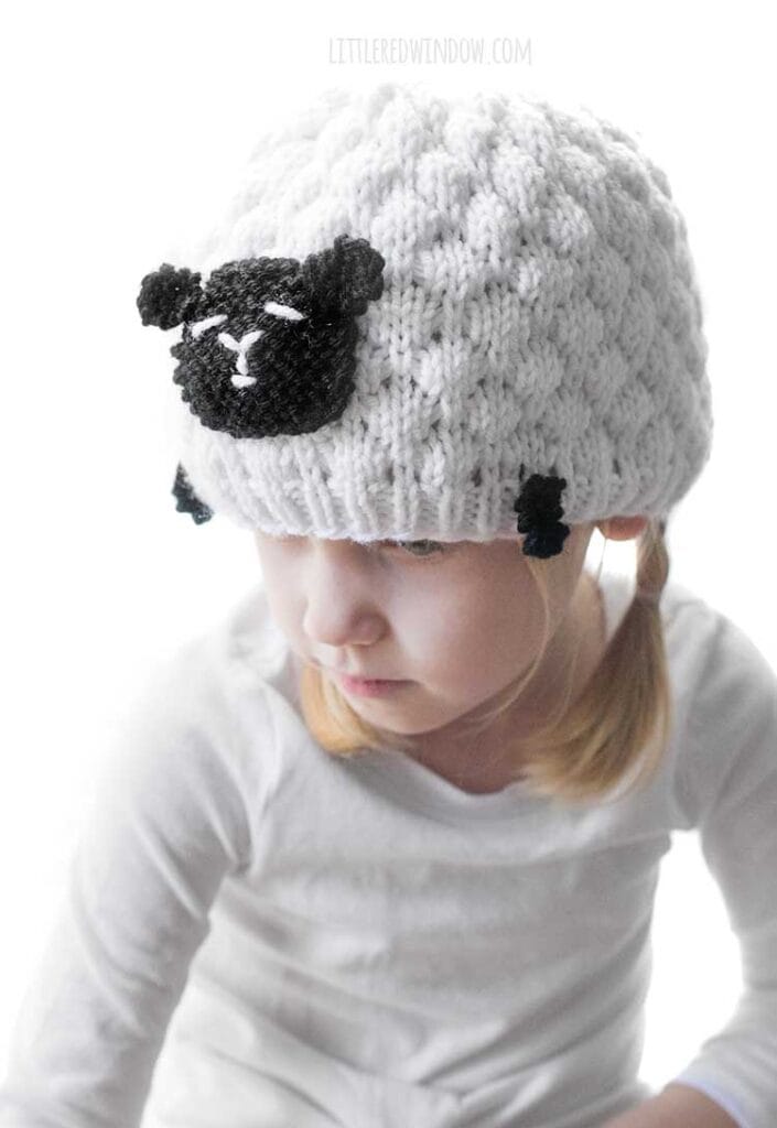 girl in white and black sheep hat looking down and to the left