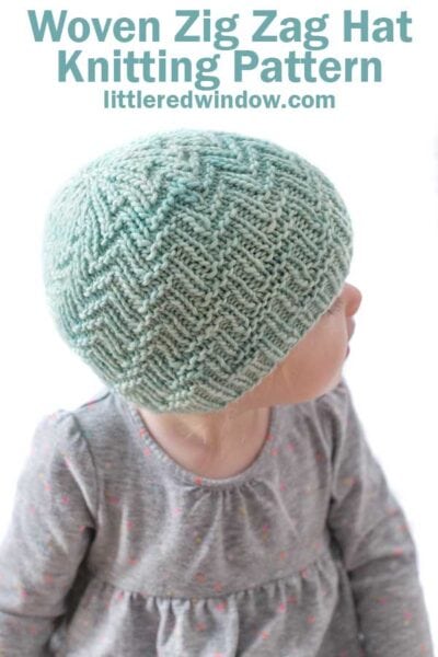little girl looking back over her left shoulder and wearing a mint knit hat with zig zag knitting pattern