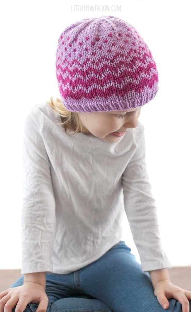 little girl wearing evaporation hat with raspberry zig zags on a lavender knit hat