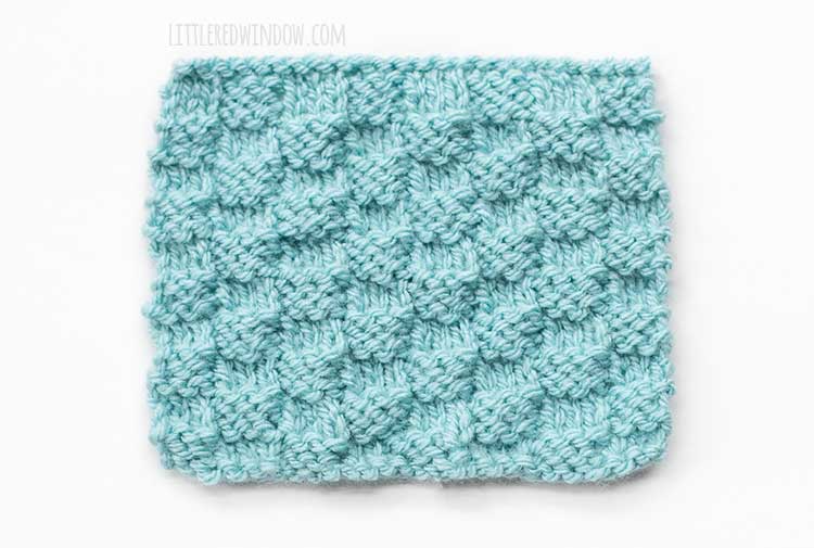 the wrong side of a light blue rectangle of basic checkerboard stitch knitting on a white background