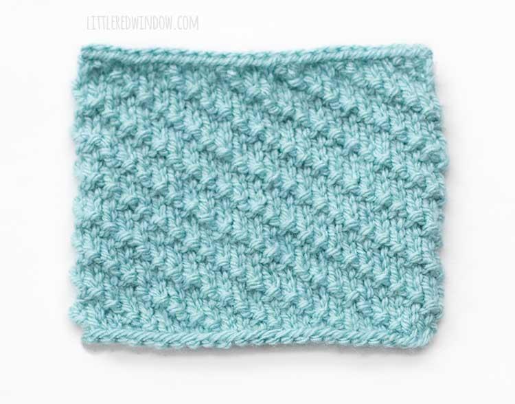 the right side of a light blue rectangle of diagonal stitch knitting on a white background