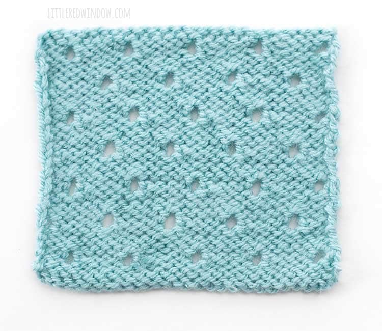 the wrong side of a light blue square swatch of basic eyelet stitch knitting on a white background